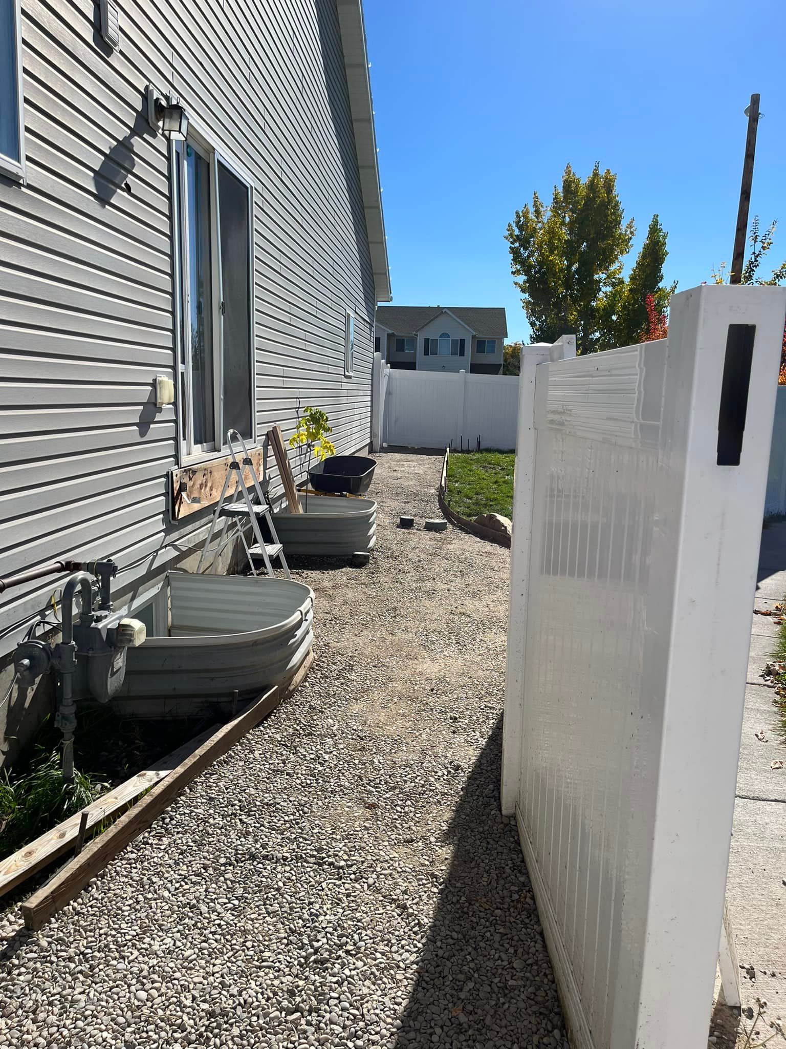 A white fence surrounds a gravel path leading to a house