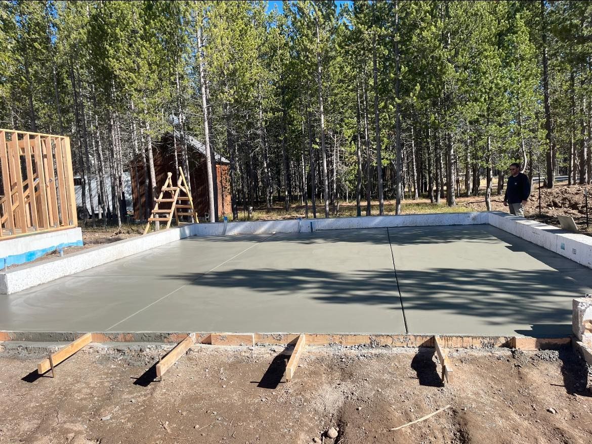 A concrete base for a house is being built in the woods