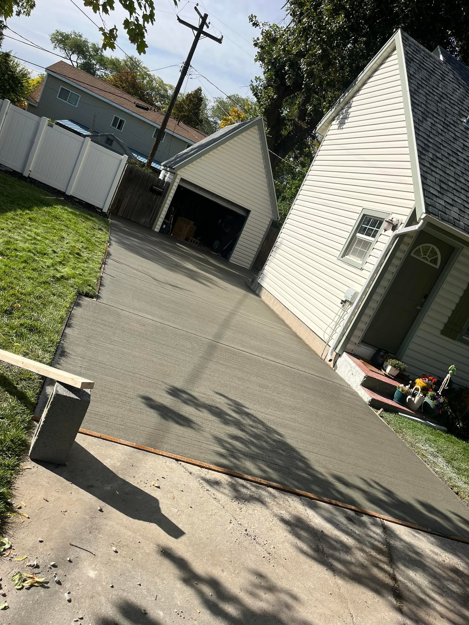 A concrete driveway leading to a white house with a garage