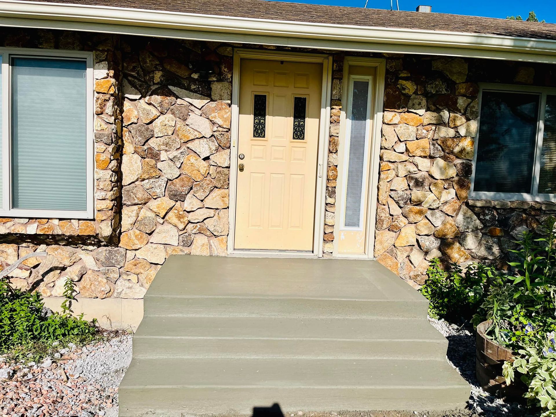 A stone house with a concrete walkway leading to the front door