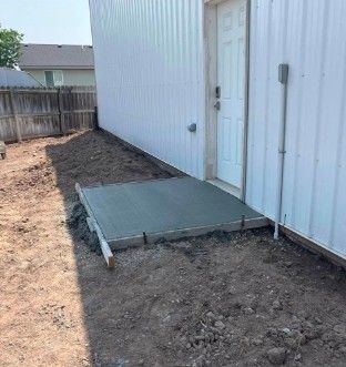 A concrete ramp is being built in front of a white building