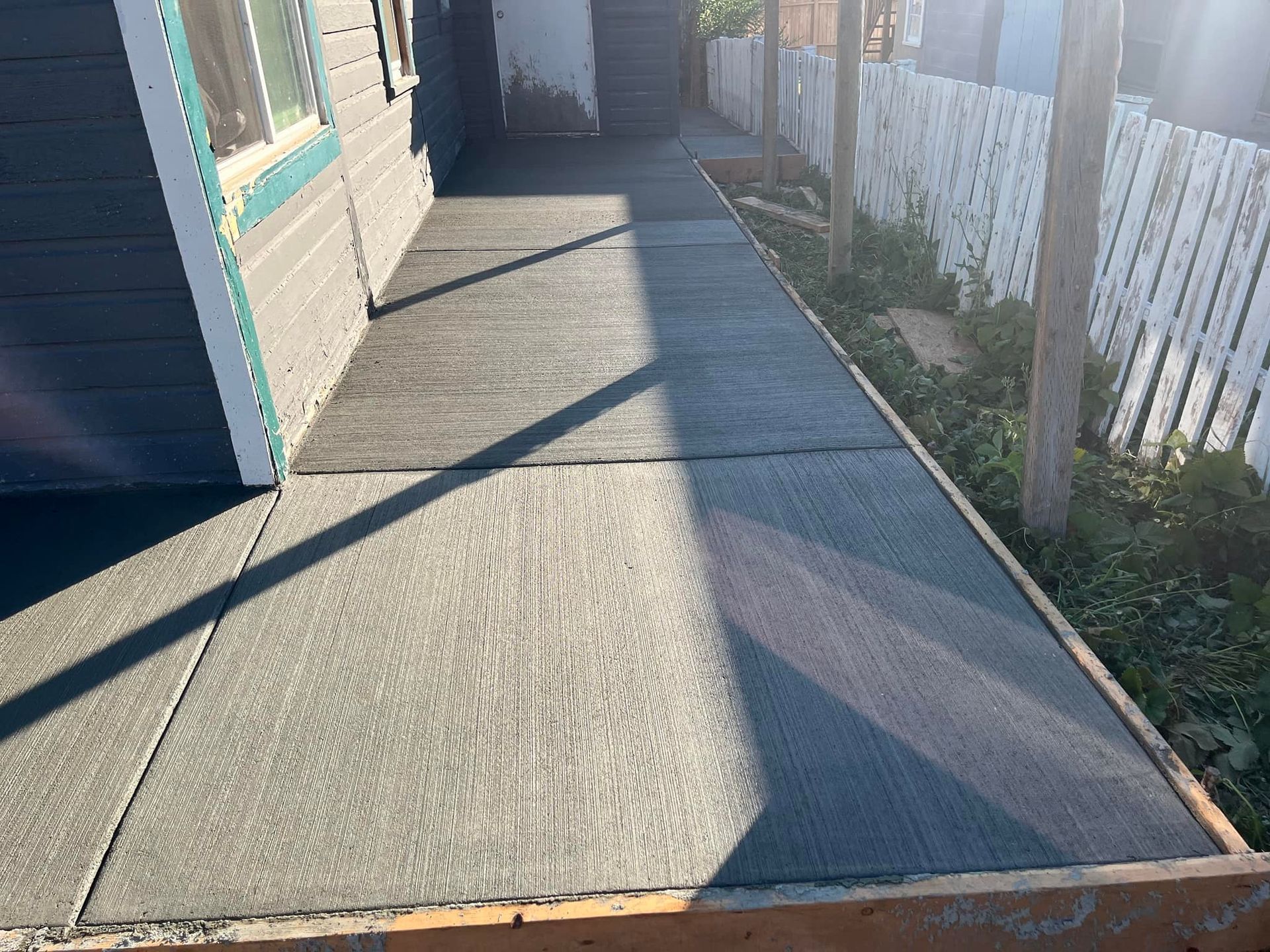 A concrete walkway is being built in front of a house