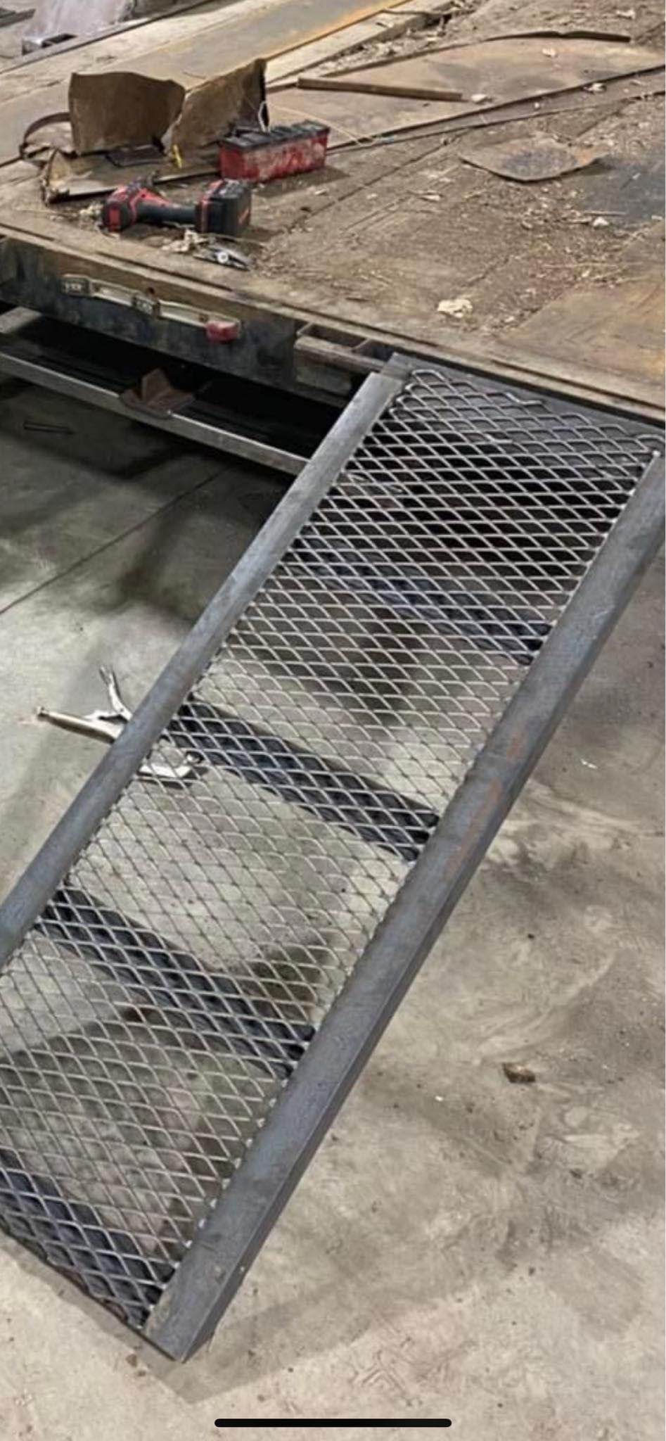 A metal ramp is sitting on the ground next to a truck