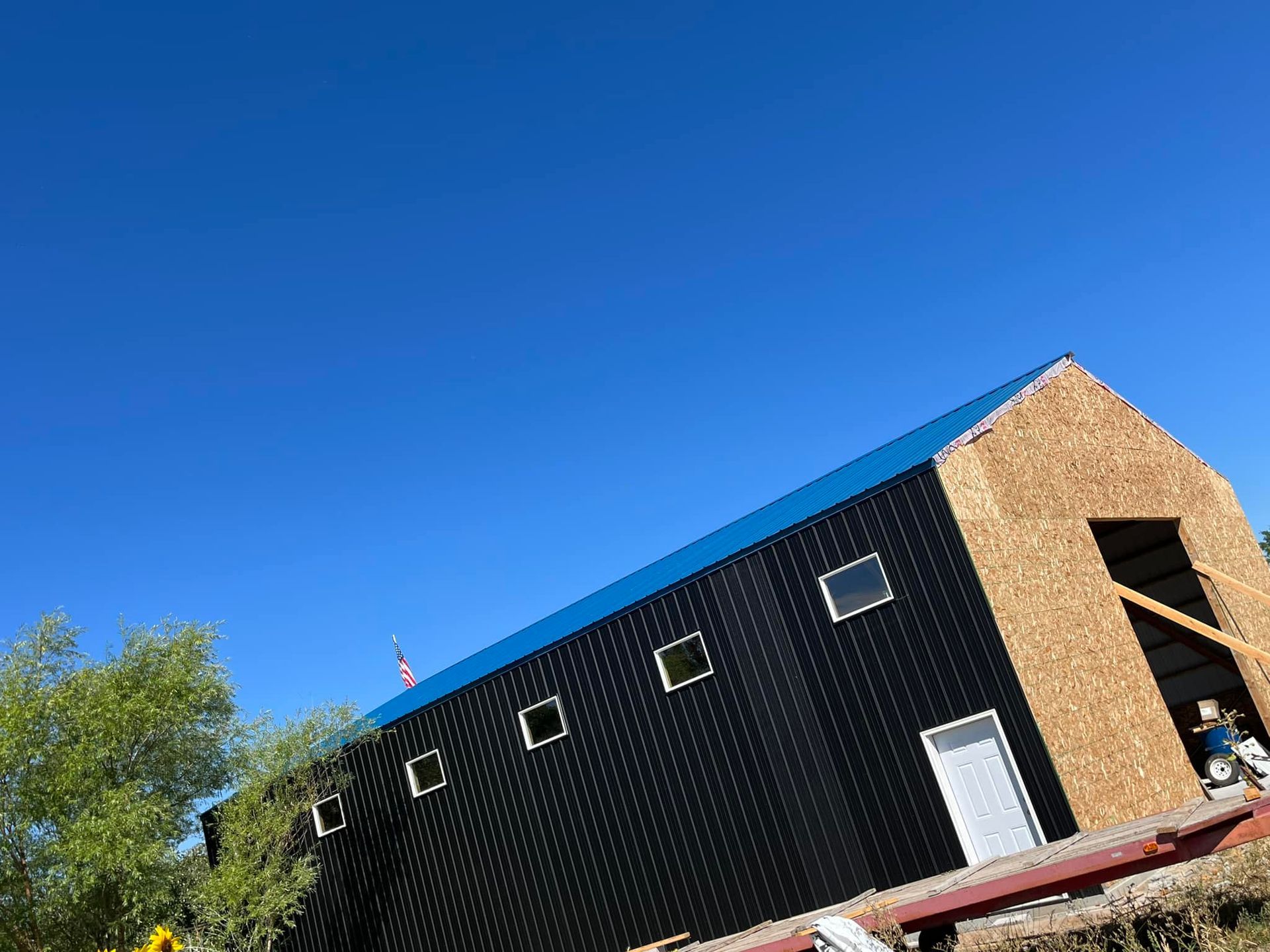 A large black building with a blue roof is being built