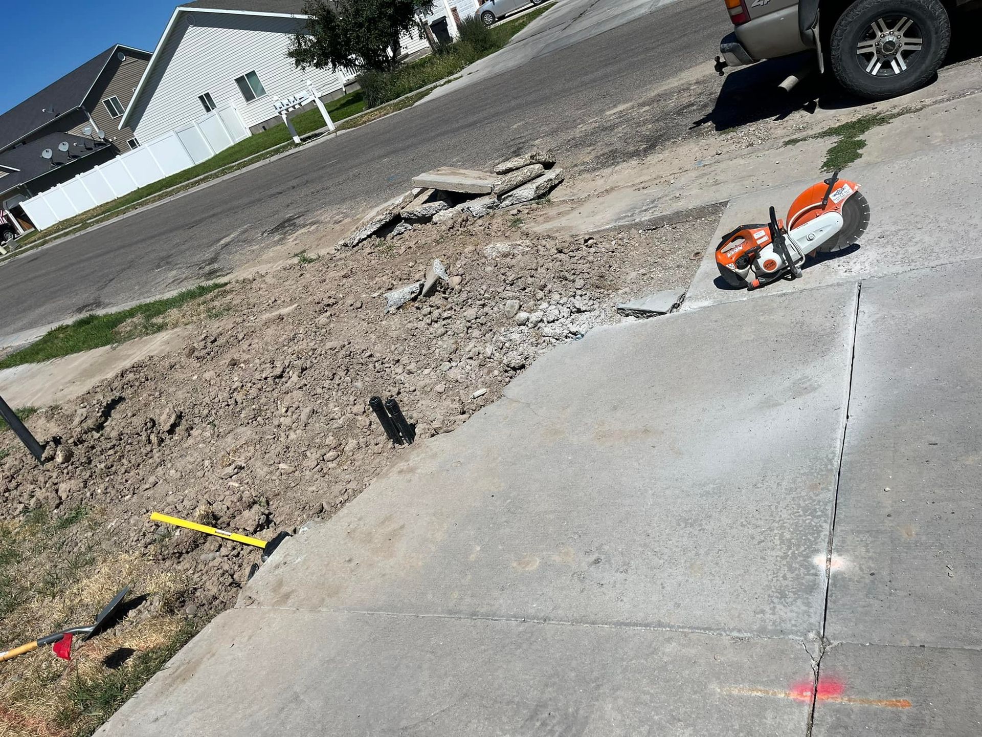 A stihl chainsaw is laying on the sidewalk next to a truck