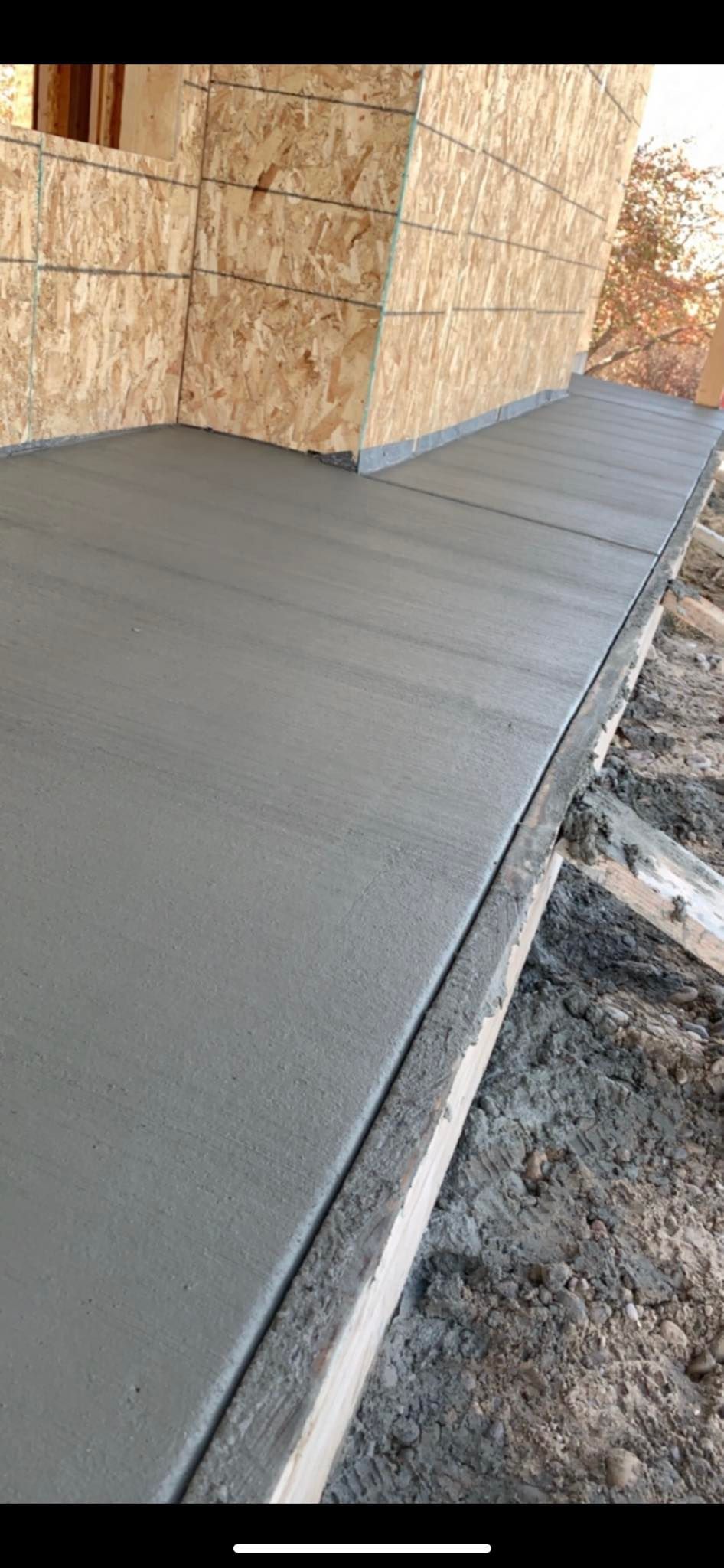 A concrete walkway is being built in front of a house under construction