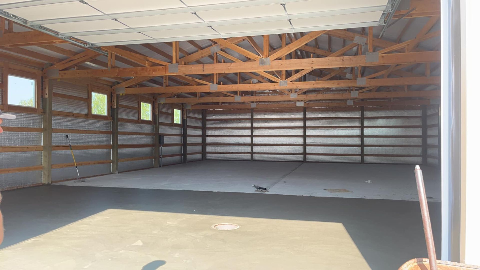 A large empty garage with wooden beams and a concrete floor
