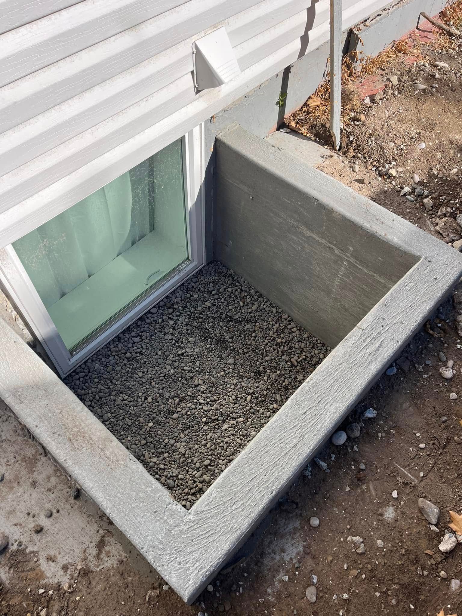 A window well in the ground next to a house