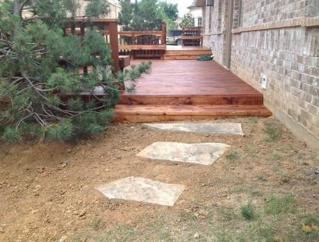A wooden deck with steps and a stone walkway leading to it