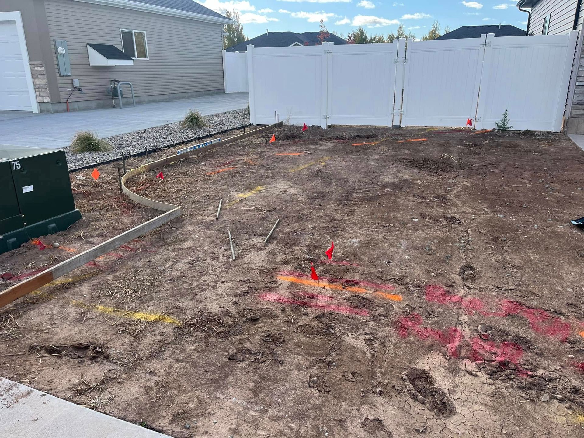 A dirt yard with a white fence in the background