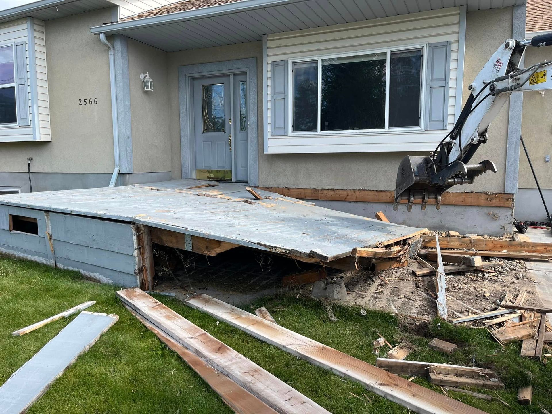 A house is being demolished with a crane in the backyard