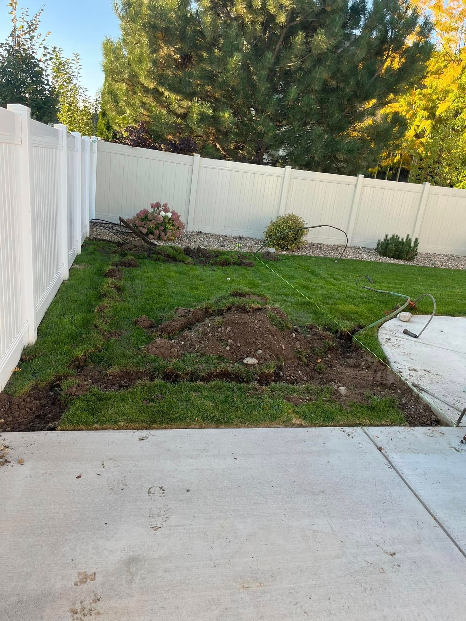 A backyard with a white fence and a concrete walkway