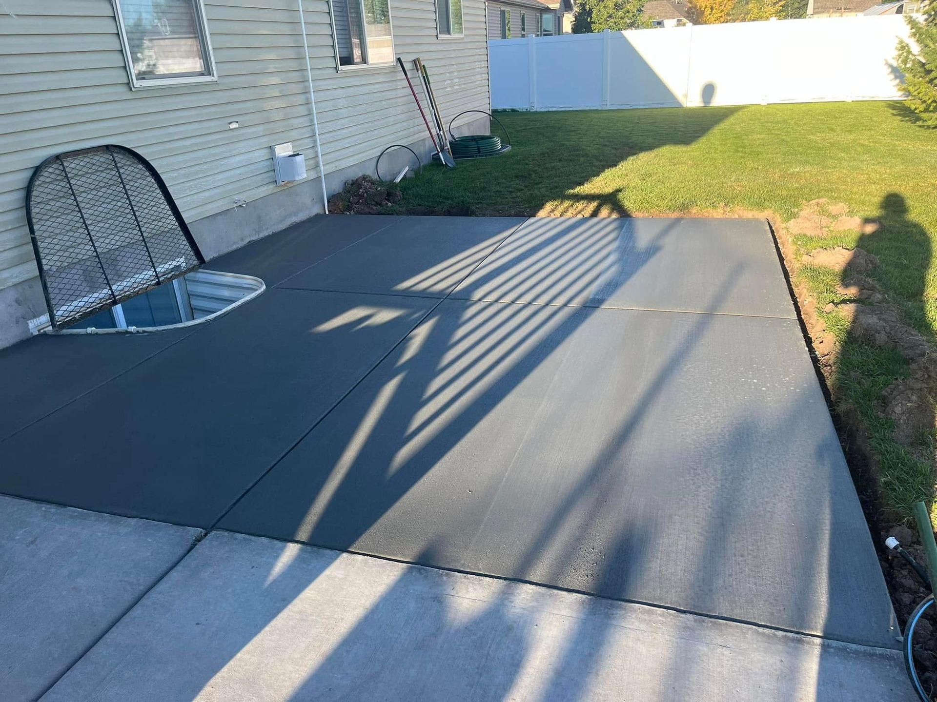 A concrete patio is being built in the backyard of a house
