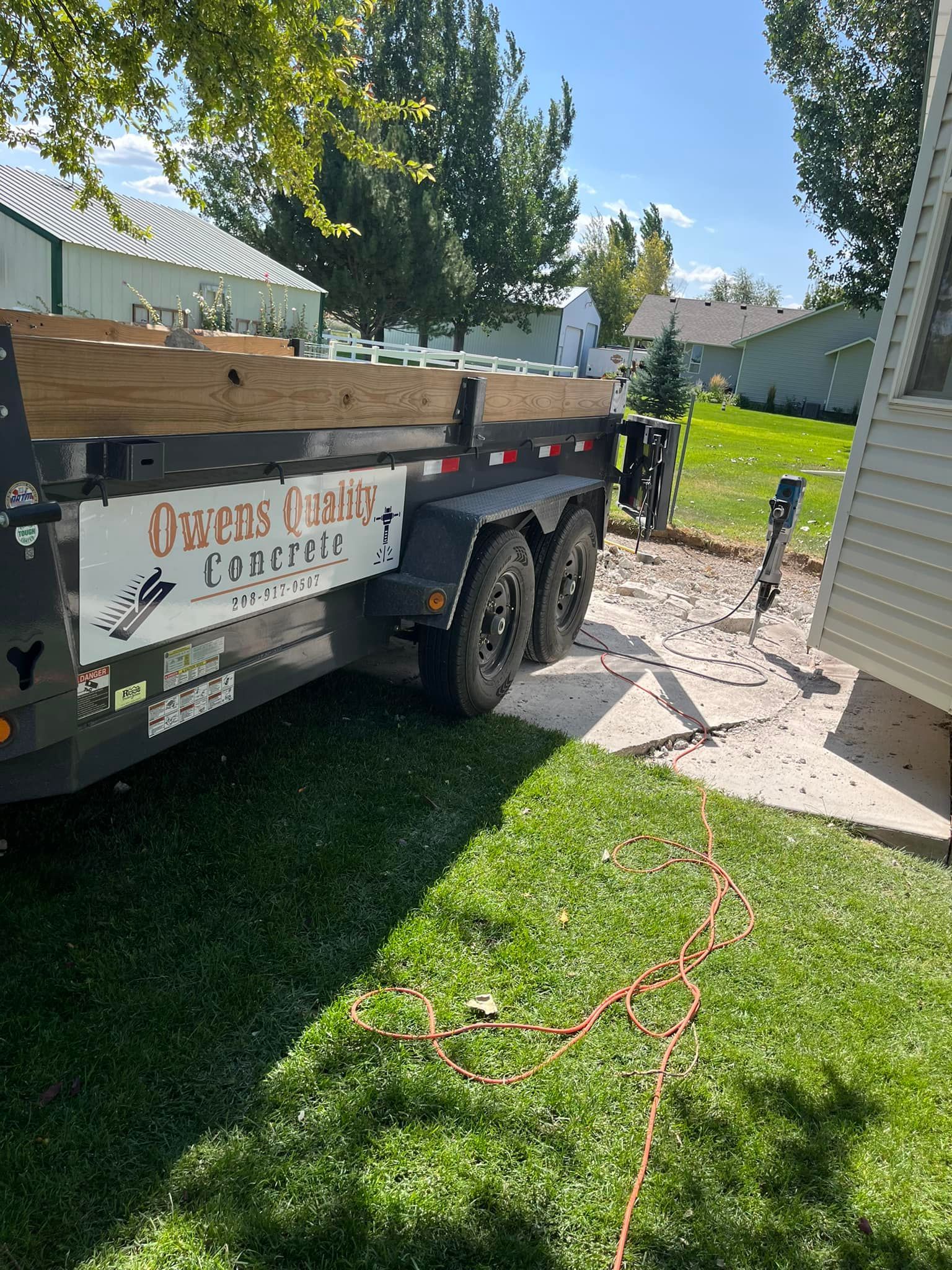 A dump truck is parked in the grass next to a house