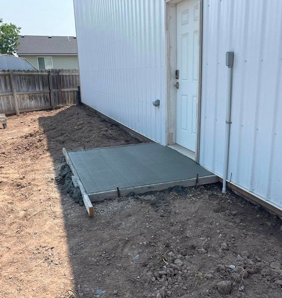 A concrete walkway is being built in front of a white building