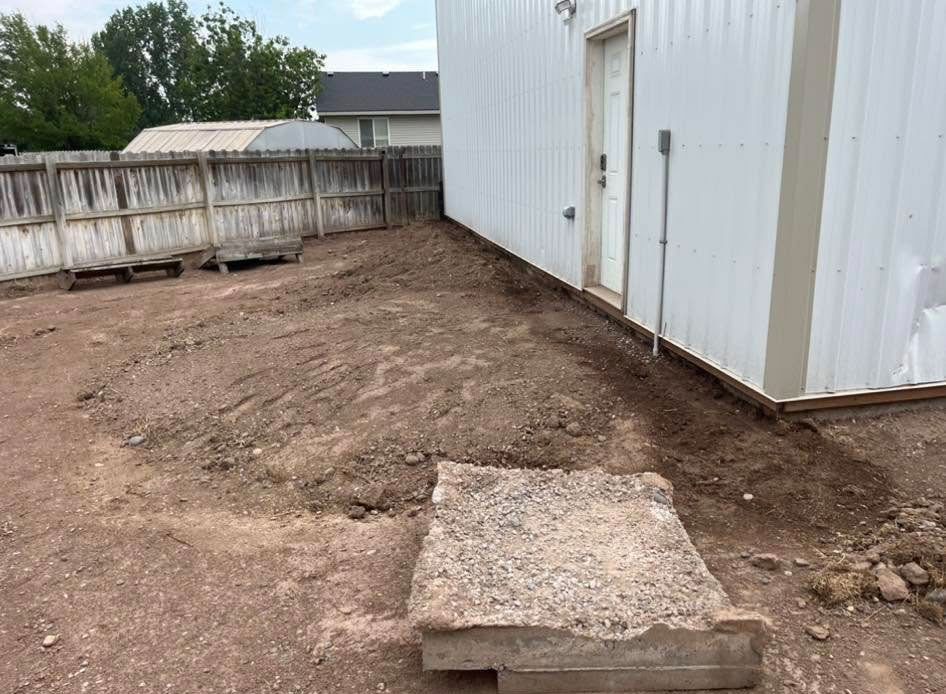 A concrete slab is sitting in the dirt in front of a white building