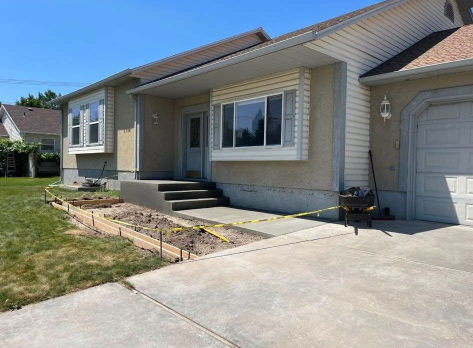 A house with a concrete walkway being built in front of it