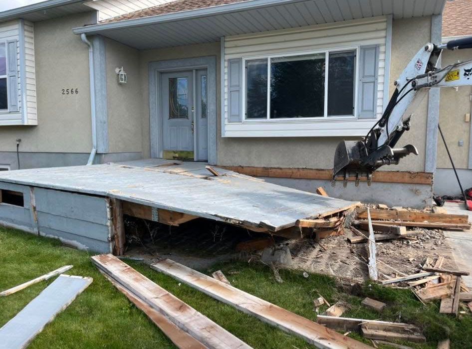 A house is being demolished with a crane in the background