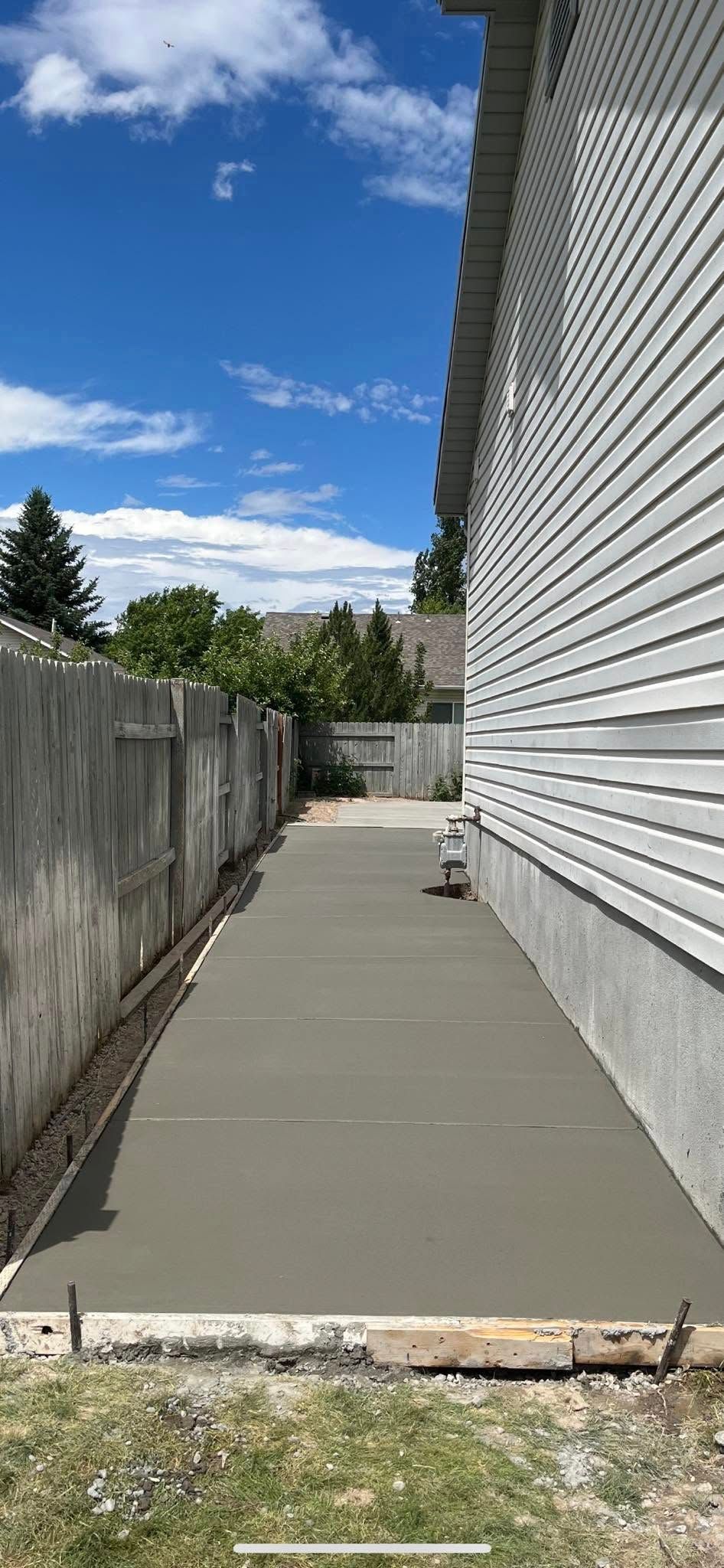 A concrete walkway is being built next to a house