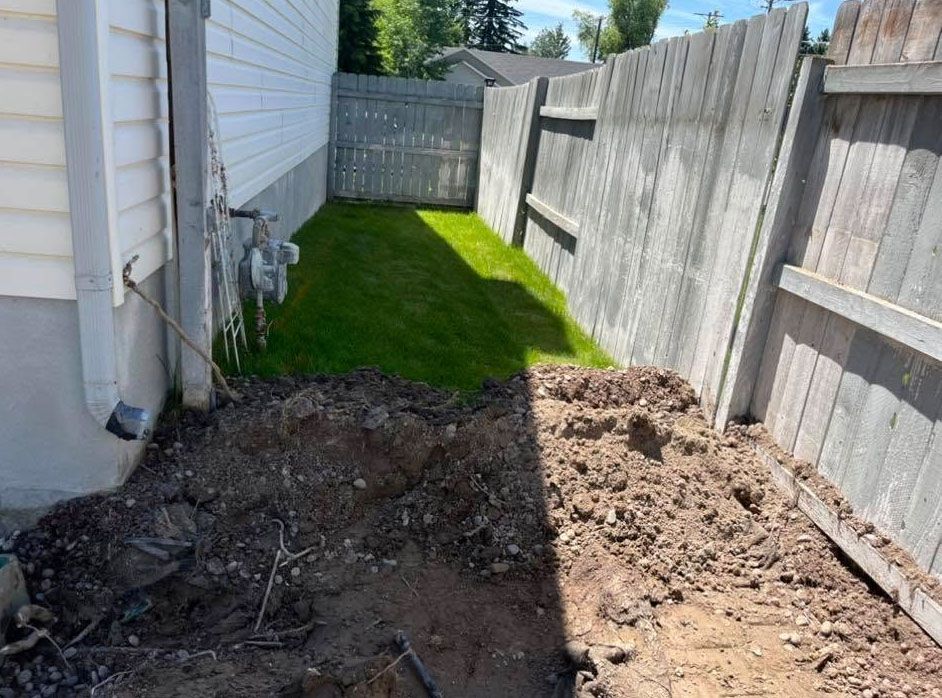 There is a hole in the ground in the backyard of a house