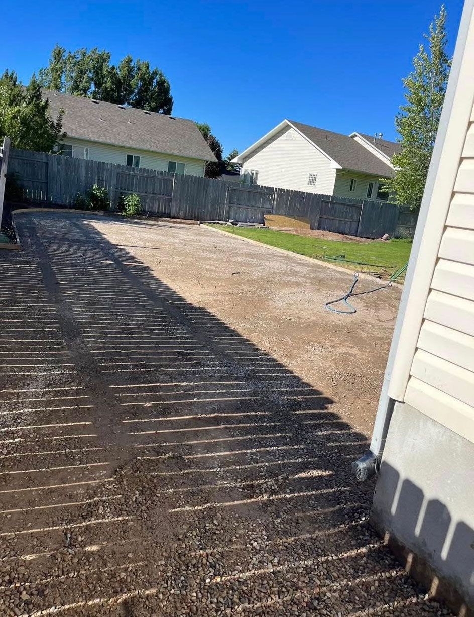 A driveway with a fence and a house in the background