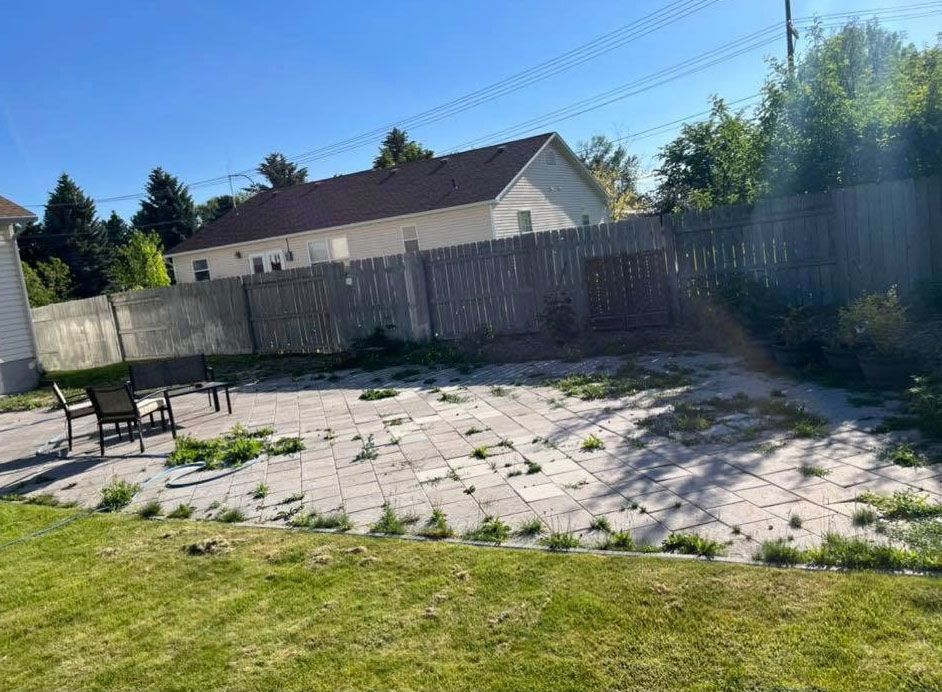 A backyard with a patio and a fence and a house in the background