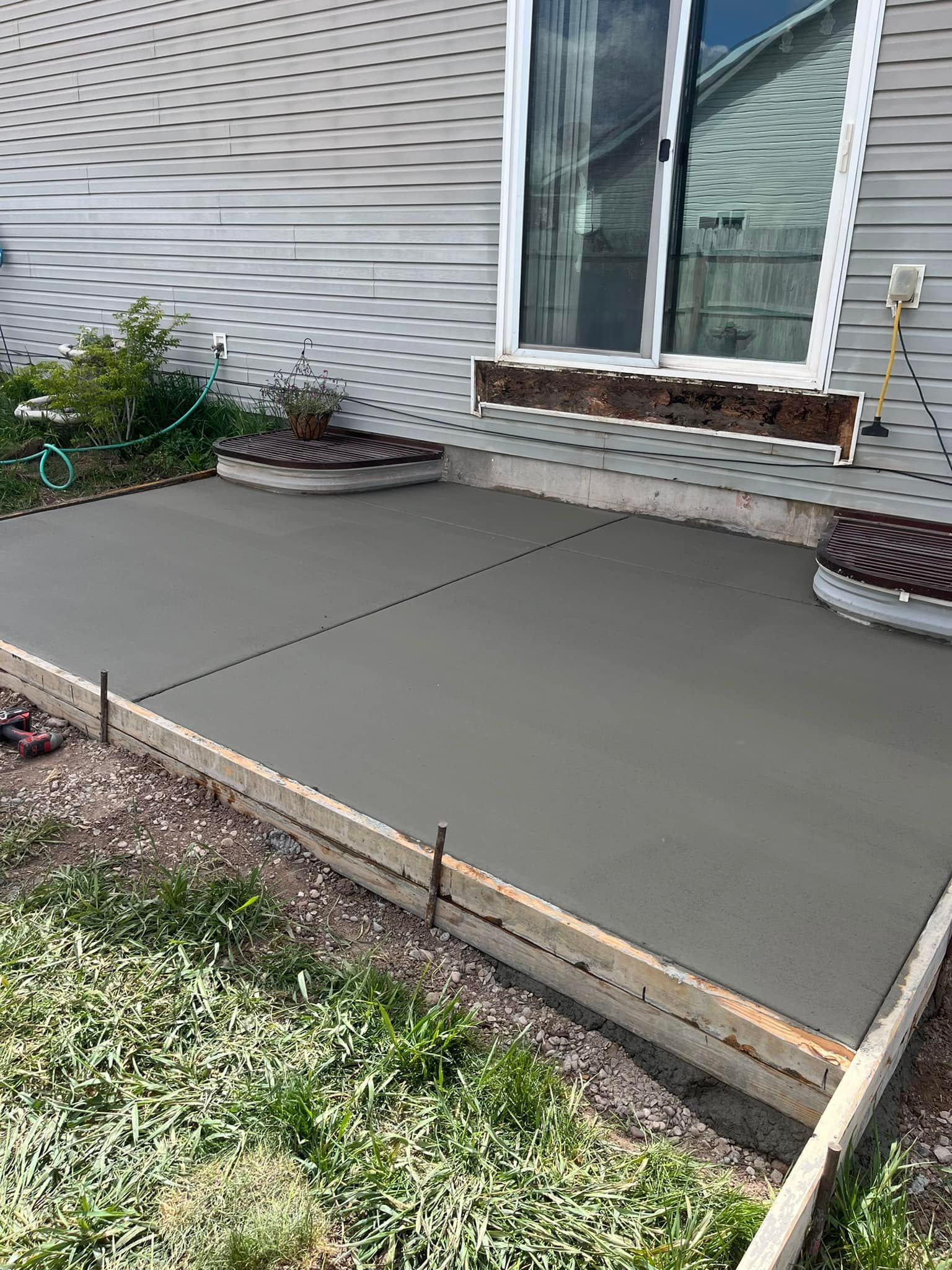 A concrete patio is being built in front of a house