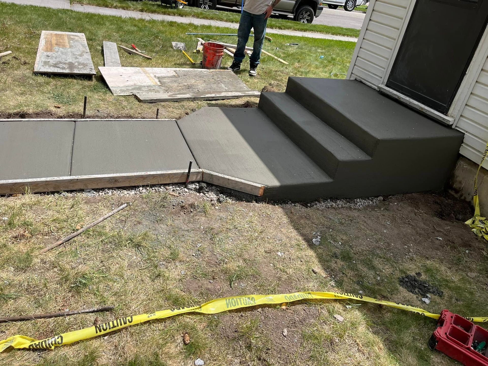 A man is standing next to a set of concrete steps being built in front of a house