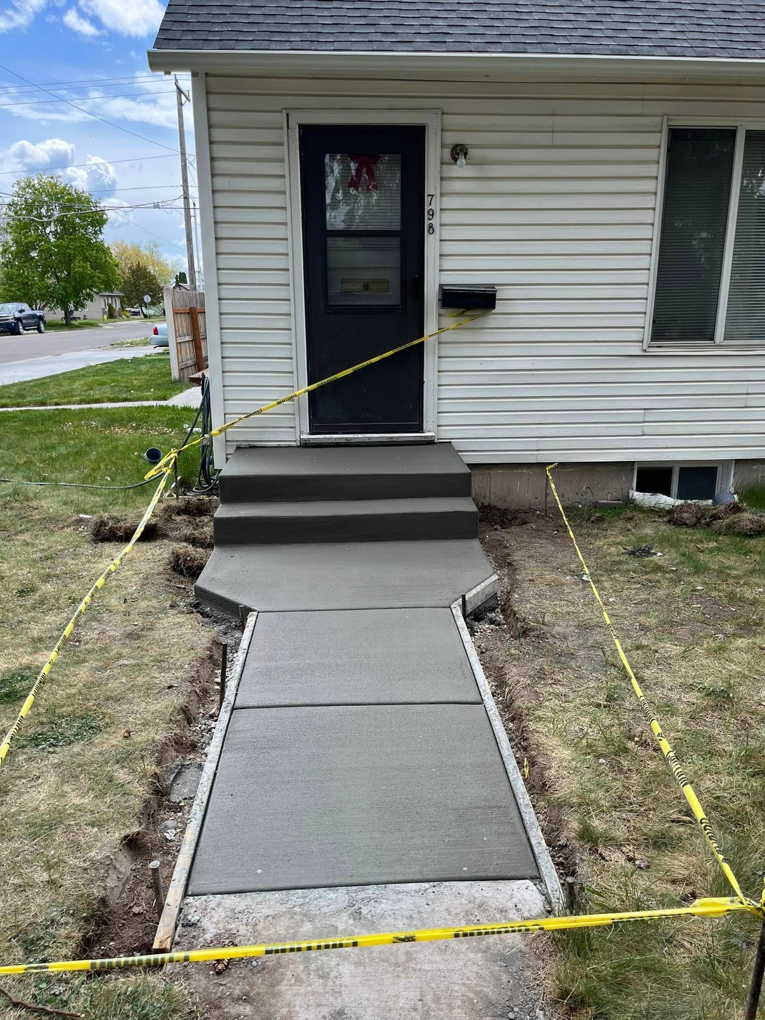 A concrete walkway is being built in front of a house