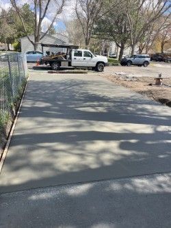 A white truck is parked in a driveway next to a fence.