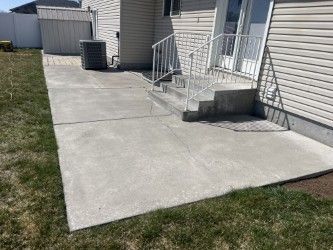 A concrete patio with stairs in front of a house.