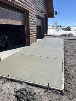 A concrete driveway is being built in front of a garage.