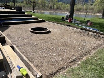 A fire pit is being built on a patio next to a river.