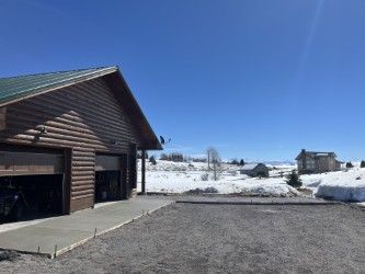 A log cabin with a garage and a driveway in the snow.