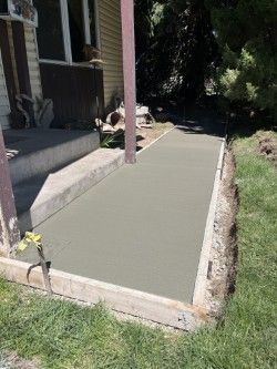 A concrete walkway is being built in front of a house.
