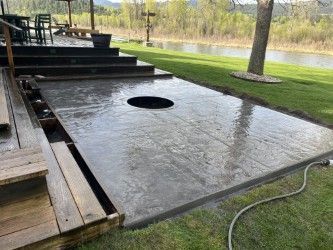 A concrete patio with a fire pit in the middle of it.