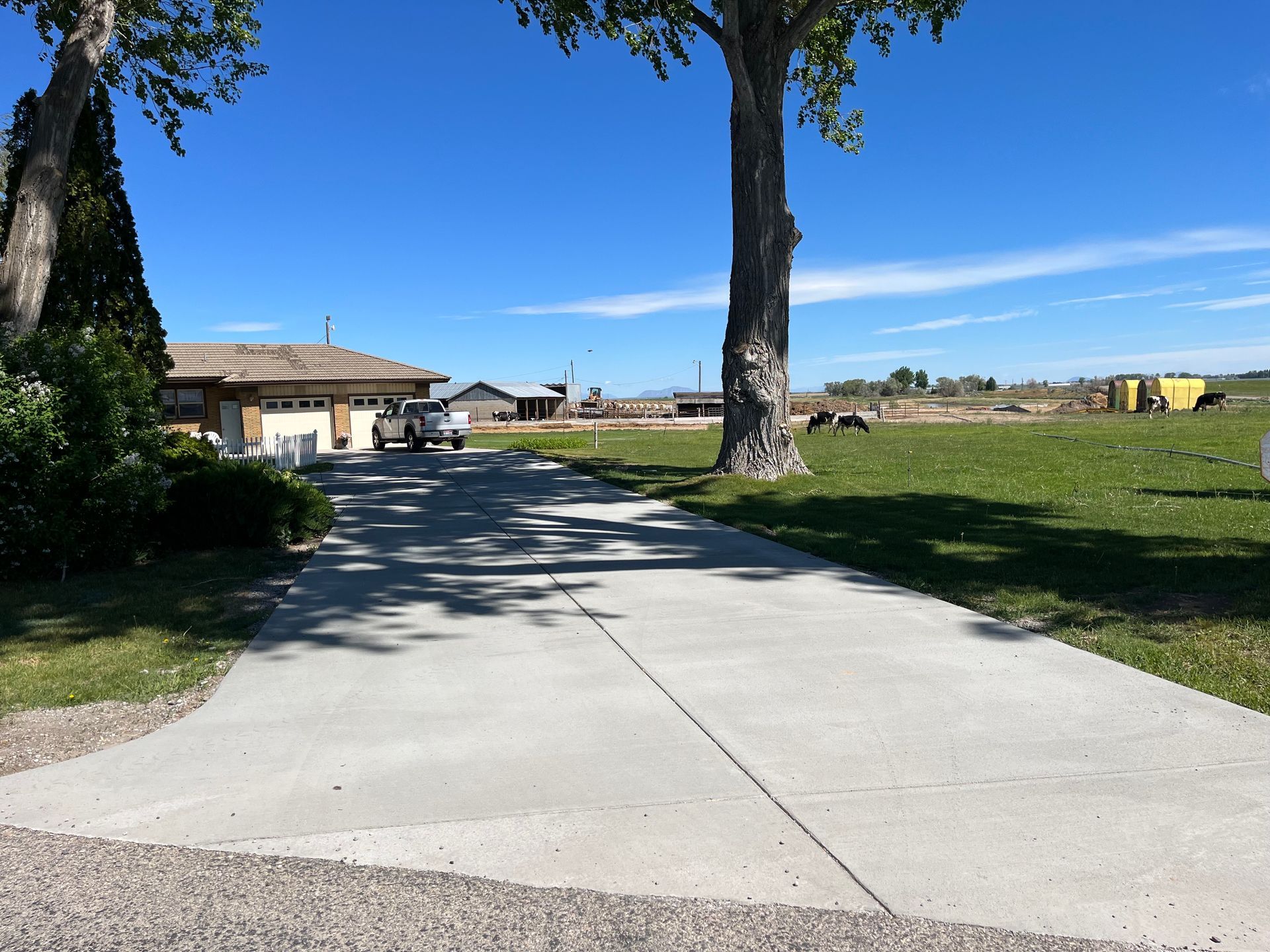 A concrete driveway with a house in the background.