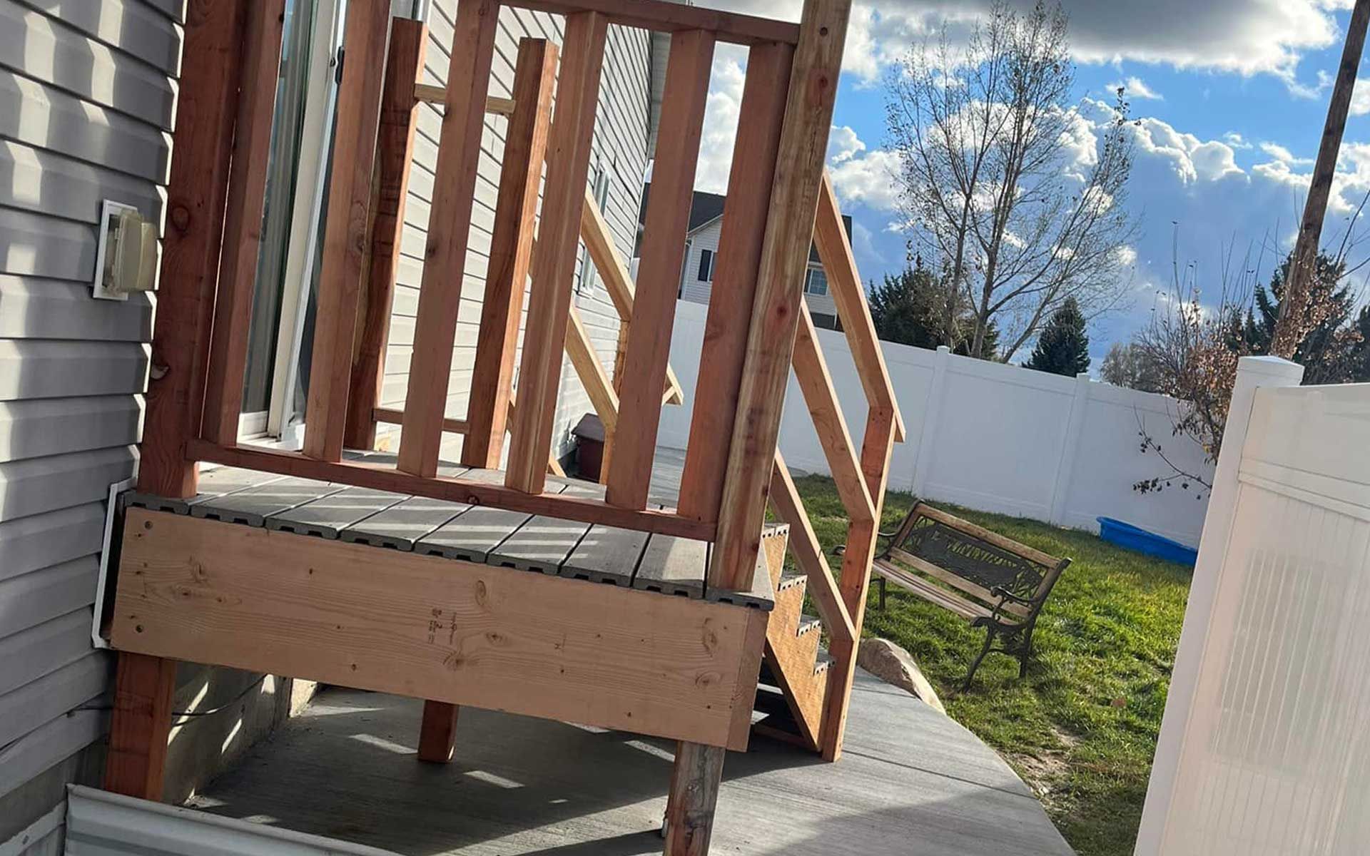 A wooden deck with stairs is being built on the side of a house.