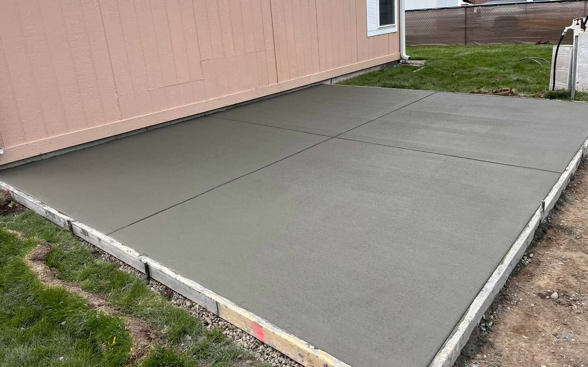 A concrete driveway is being built in front of a house.
