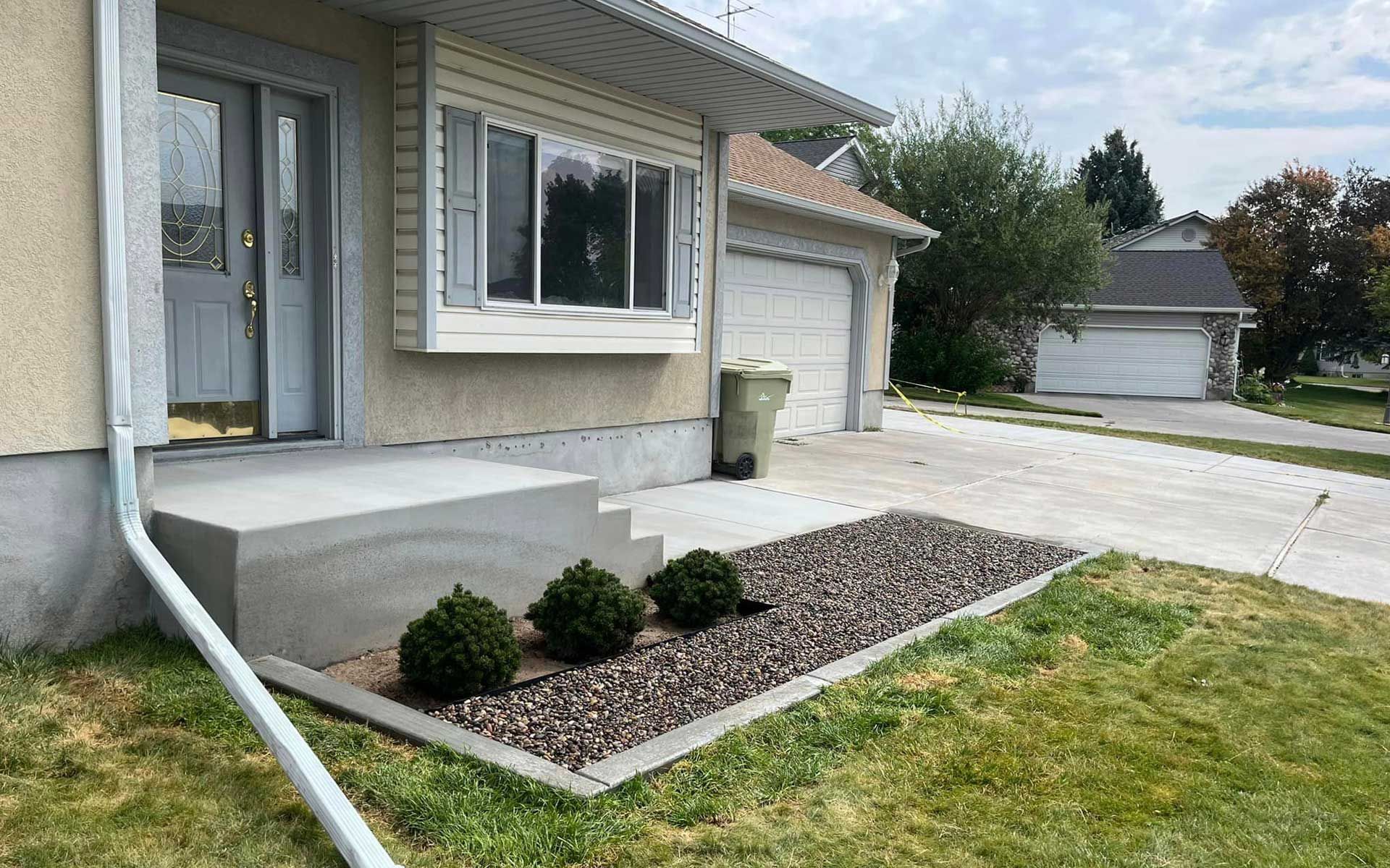 A house with a concrete porch and stairs in front of it.