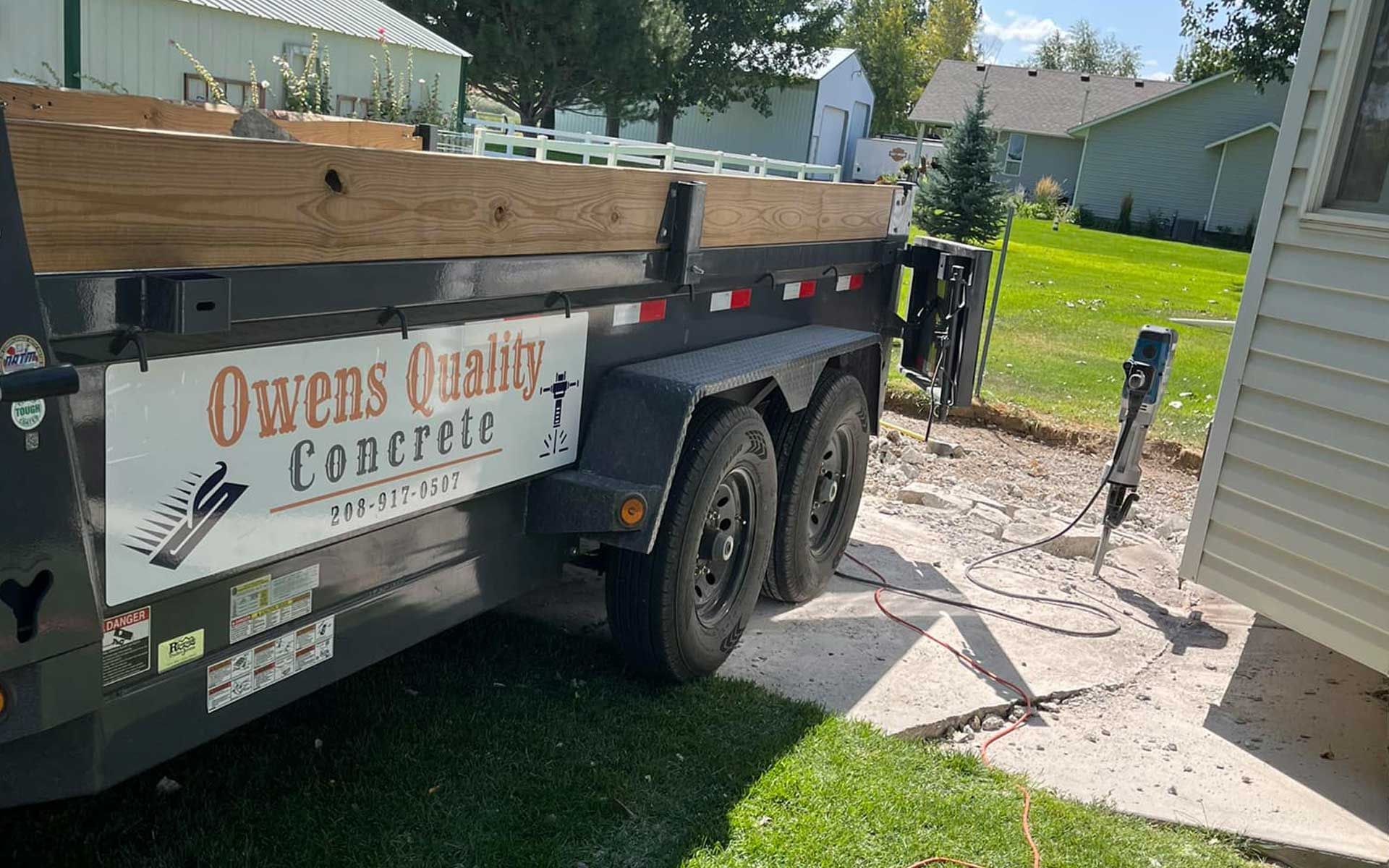 A trailer for owens quality concrete is parked in front of a house.