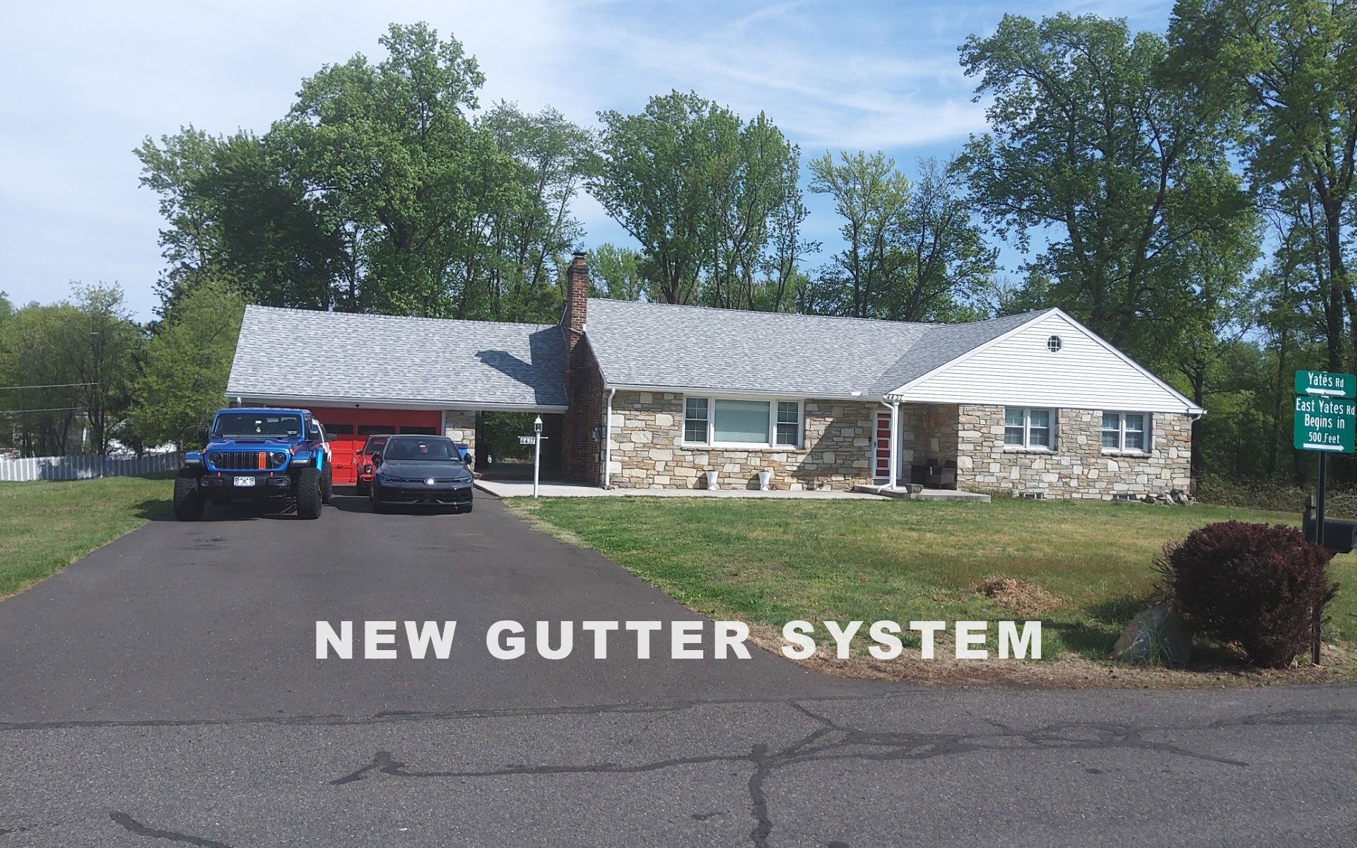 House with new gray gutter system, blue SUV parked in driveway, and NEW GUTTER SYSTEM text overlay