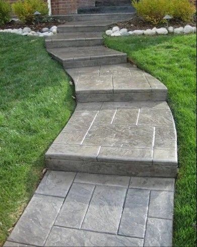 Stone steps leading up a curved walkway through green grass.