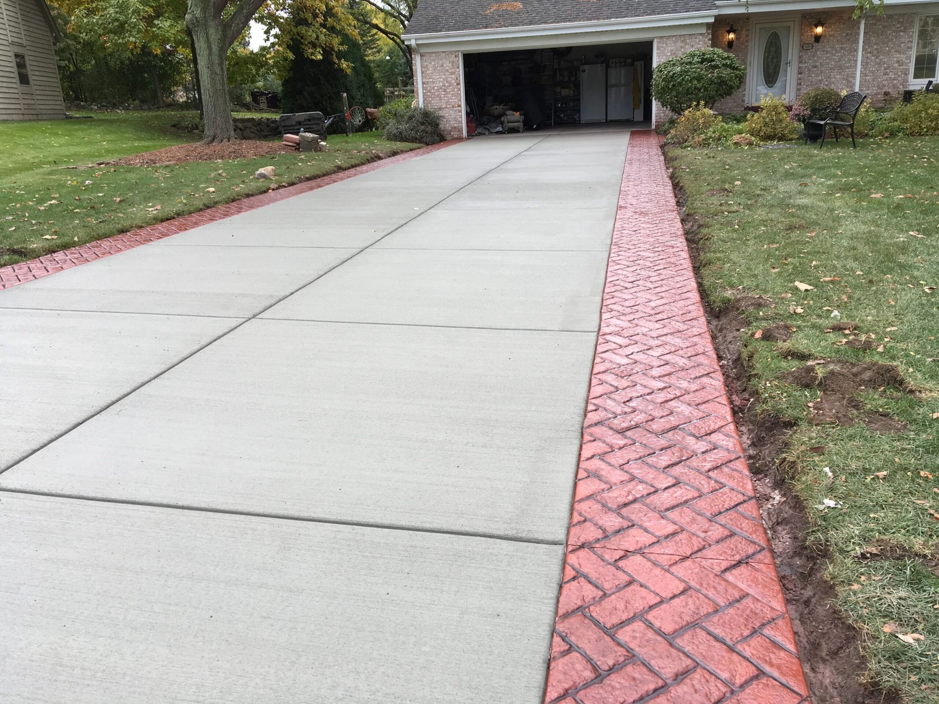 Concrete driveway with red brick border, leading to a garage.