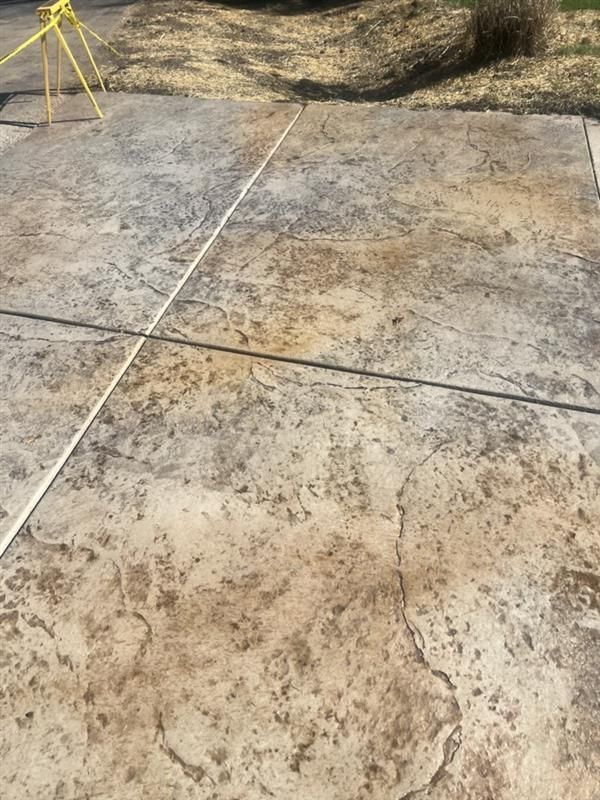 Stamped concrete driveway with tan and brown coloring, power wash lines visible.