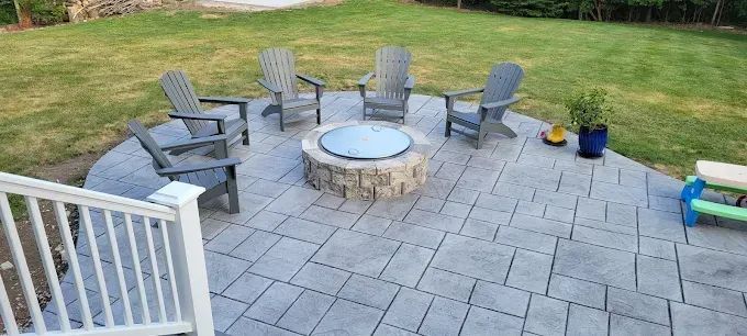 Stone patio with brick-red border curves in front of a building with white and dark brown accents.