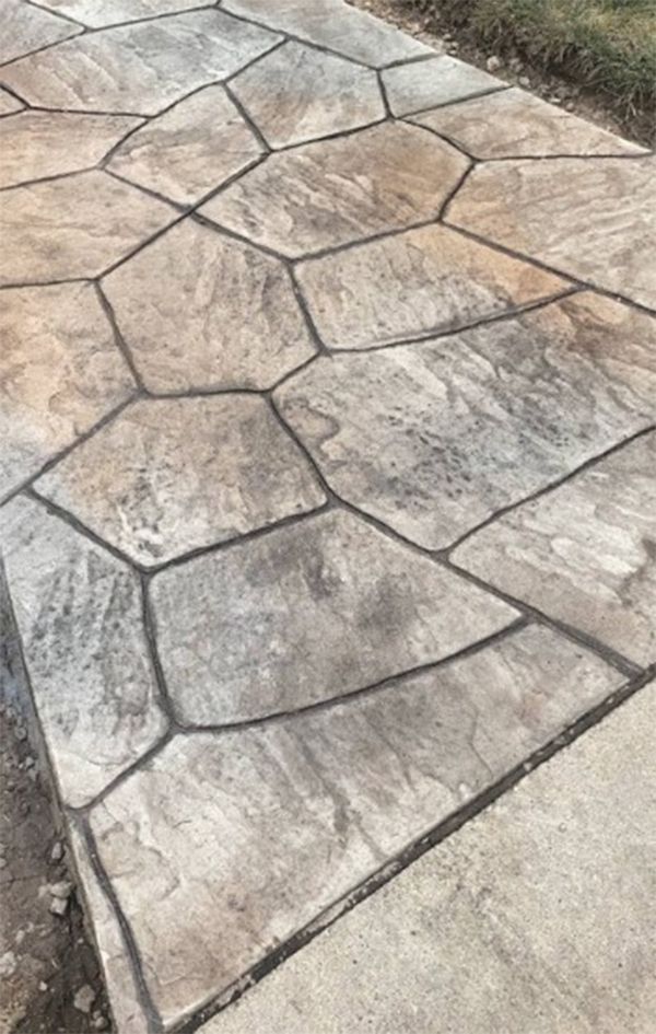 Concrete walkway with irregular stone pattern, light brown and gray with dark grout lines.
