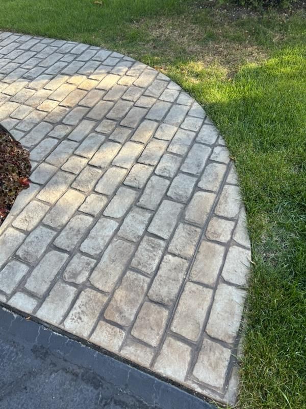Brick pathway curving alongside green grass.