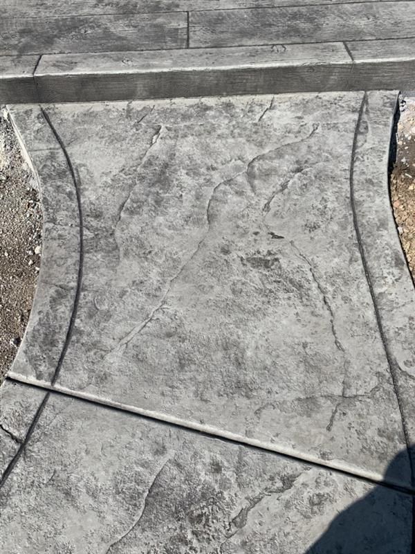 Gray stamped concrete walkway with curved edges and a textured surface.