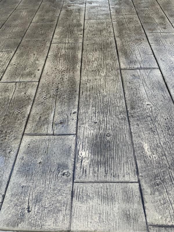 Concrete flooring with a weathered wood plank pattern in varying shades of gray.